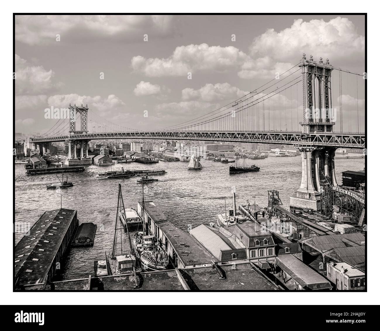 Brooklyn Bridge 1900's Vintage B&W vista attraversando la scena del fiume Est Manhattan New York USA il Ponte di Brooklyn è un ponte ibrido con stalla via cavo/sospensione a New York City, che attraversa l'East River tra i quartieri di Manhattan e Brooklyn. Aperto il 24 maggio 1883, il ponte di Brooklyn fu il primo incrocio fisso del fiume East. Fu anche il ponte sospeso più lungo del mondo al momento della sua apertura, con una distanza principale di 1.595,5 m (486,3 piedi) e un ponte di 127 m (38,7 piedi) sopra l'acqua media alta. Foto Stock