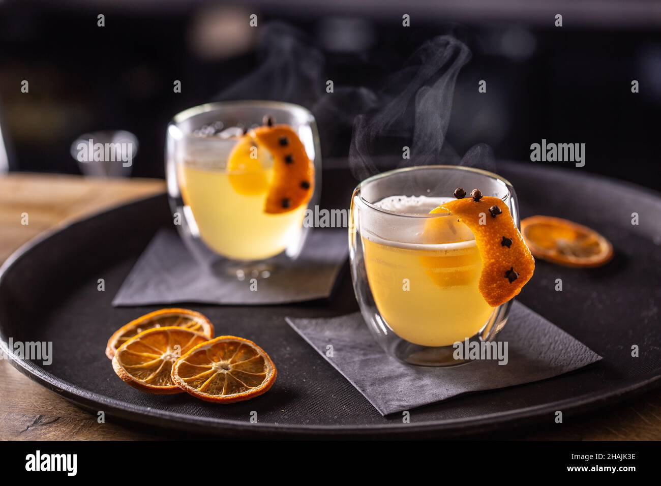 Bevanda CALDA TODDY a base di whiskey, sciroppo semplice, acqua calda, chiodi di garofano e scorza d'arancia pronti per i clienti nel pub al banco del bar. Foto Stock