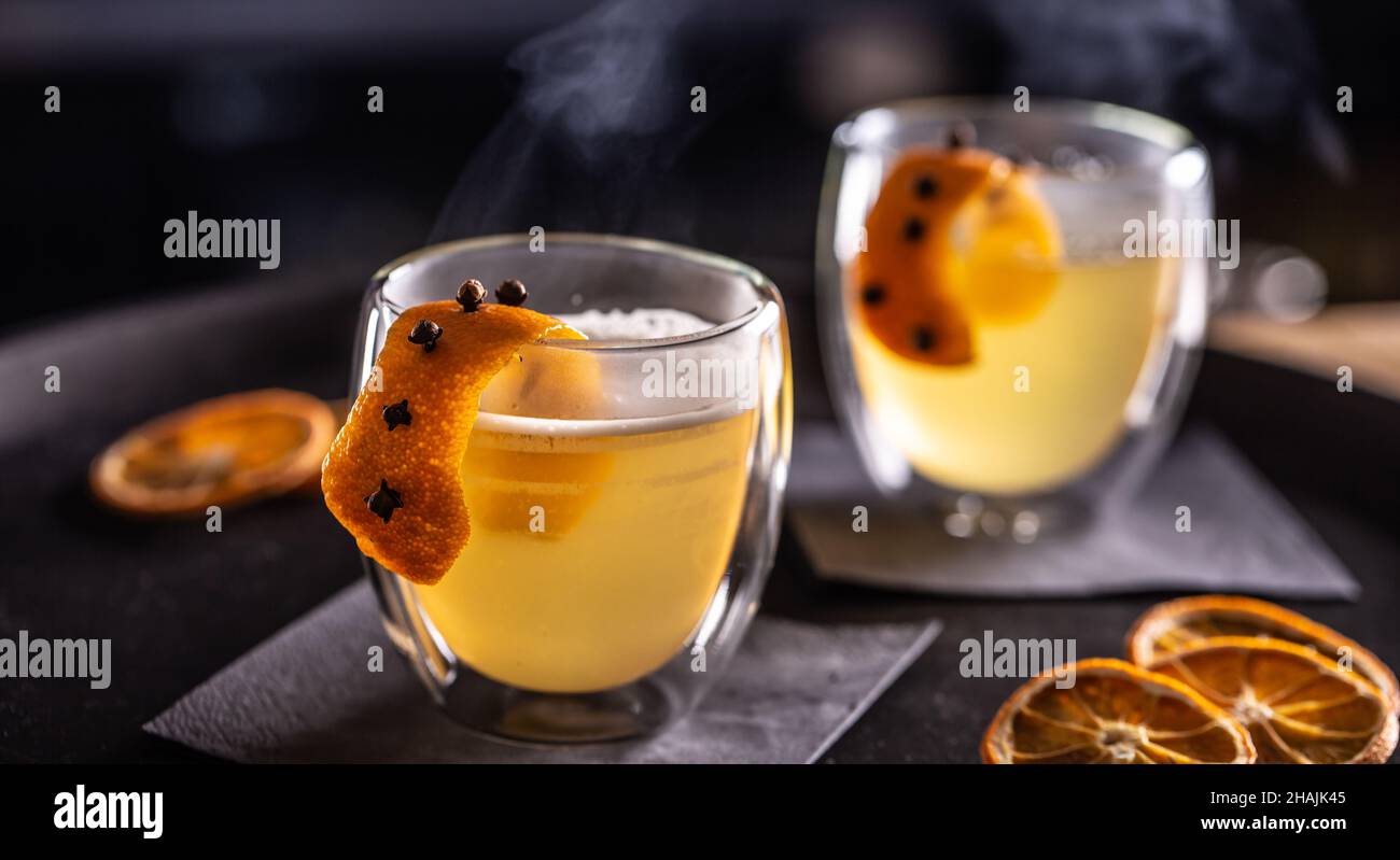 Bevanda CALDA TODDY a base di whiskey, sciroppo semplice, acqua calda, chiodi di garofano e scorza d'arancia pronti per i clienti nel pub al banco del bar. Foto Stock