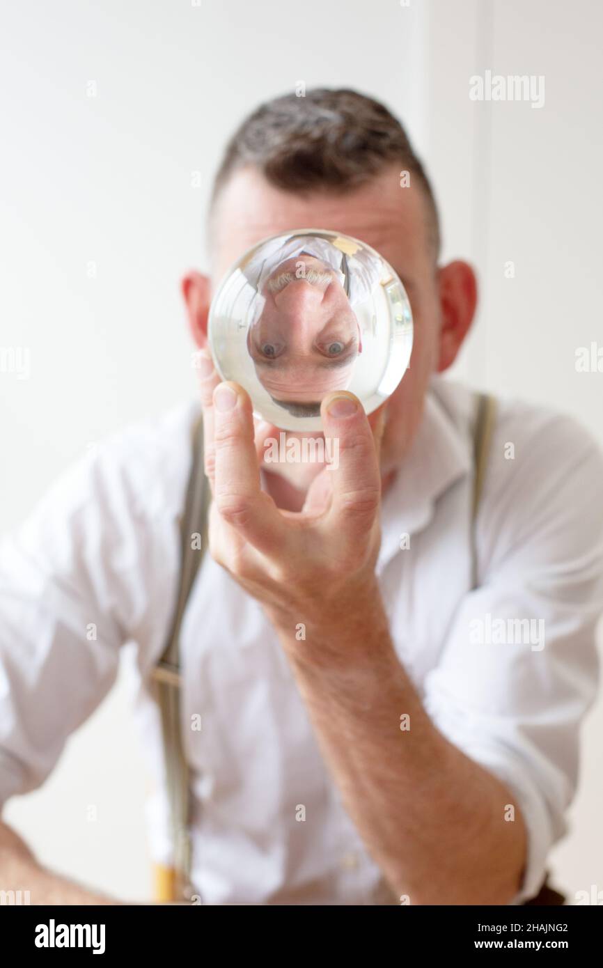 bell'uomo nel suo 50s guarda una palla di cristallo Foto Stock