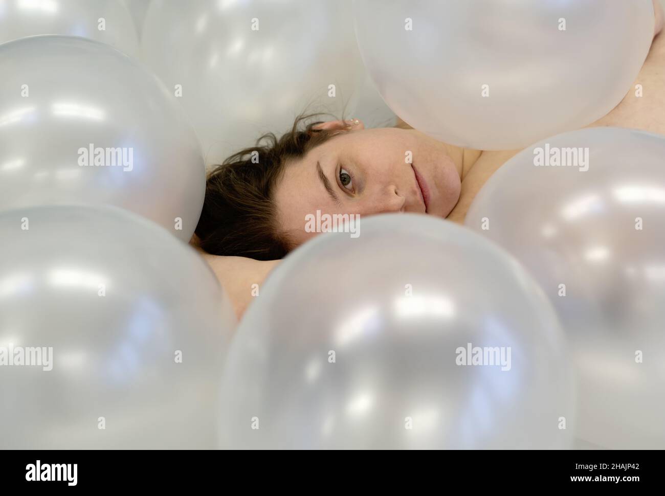 Ritratto arte vista dall'alto a bello giovane donna faccia con capelli brunette tra bianco iridescente palloncini, bellezza moda concetto, copia spazio Foto Stock