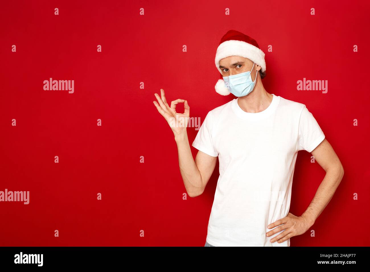 Uomo eccitato in abiti casual maglietta bianca, mostra il segno ok evidenziato sfondo rosso spazio per il testo Foto Stock