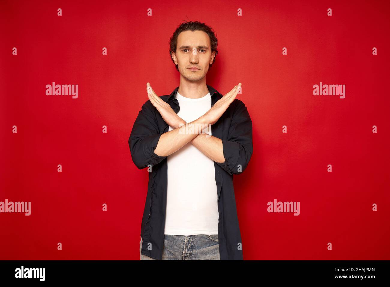 grave negativo uomo infelice triste mani incrociate mostra no stop rifiuto segno isolato su sfondo rosso con spazio libero per il testo. concetto di protesta, disaccordo, blocco, timeout, gioco over. Foto di alta qualità Foto Stock