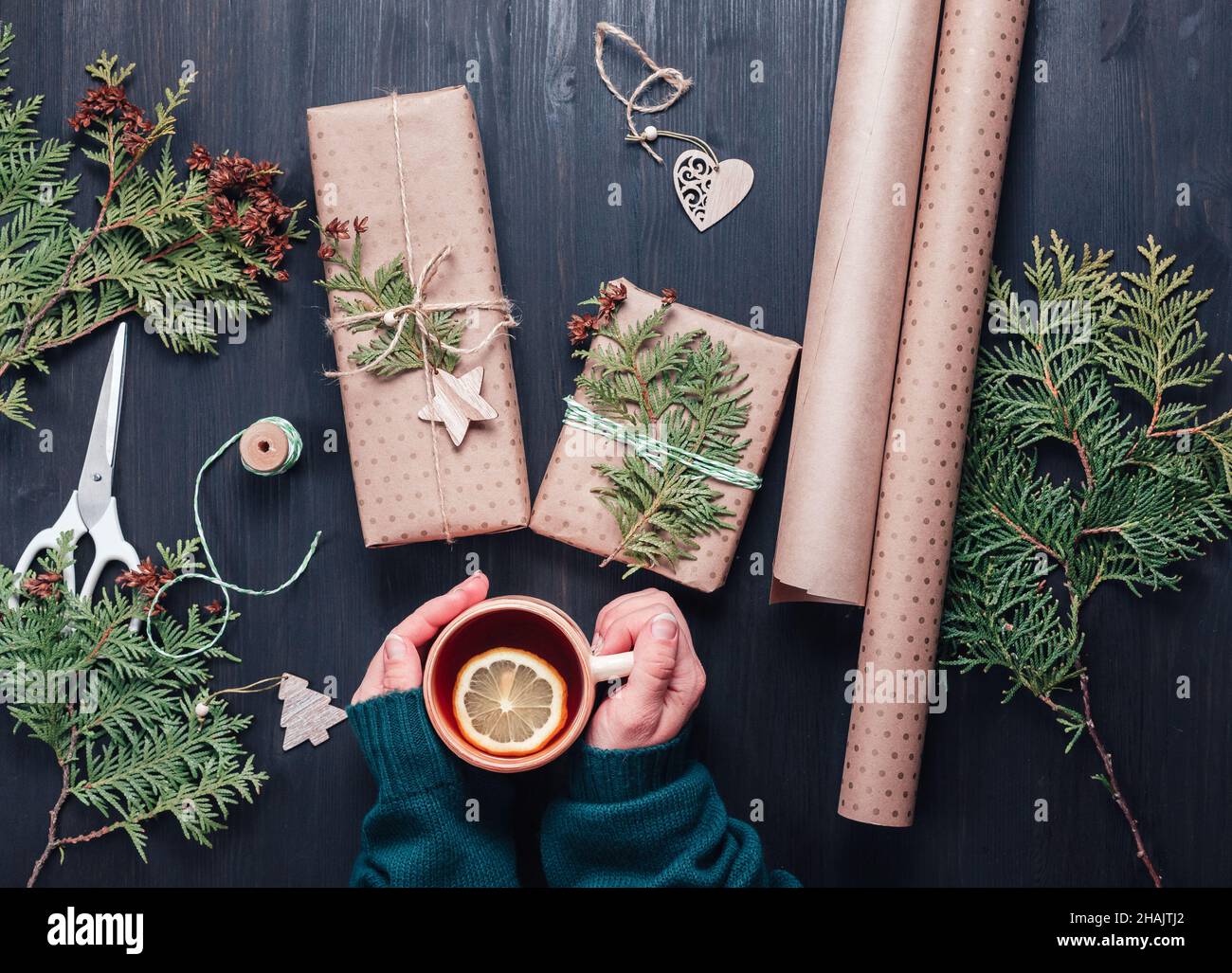 Confezione regalo di Natale in carta artigianale. Una tazza di tè caldo in mani femminili Foto Stock