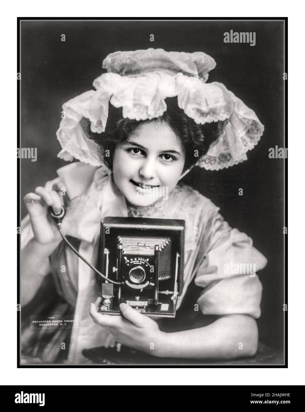 La fotografia pubblicitaria del 1900 mostra la ragazza giovane di 17-22 anni che ha posato con la macchina fotografica del film della piastra del Seneca Duo e che rilascia l'otturatore della lampadina dell'aria. Fotografato da Rochester Photo Press, c1909. - Photographic Apparatus & Supplies--1900-1910 - Cameras--1900-1910 - Advertises--1900-1910 - Young adults--1900-1909 Photographic prints--1900-1910. 1909 di Rochester Photo Press, Rochester, N. Y. USA Foto Stock