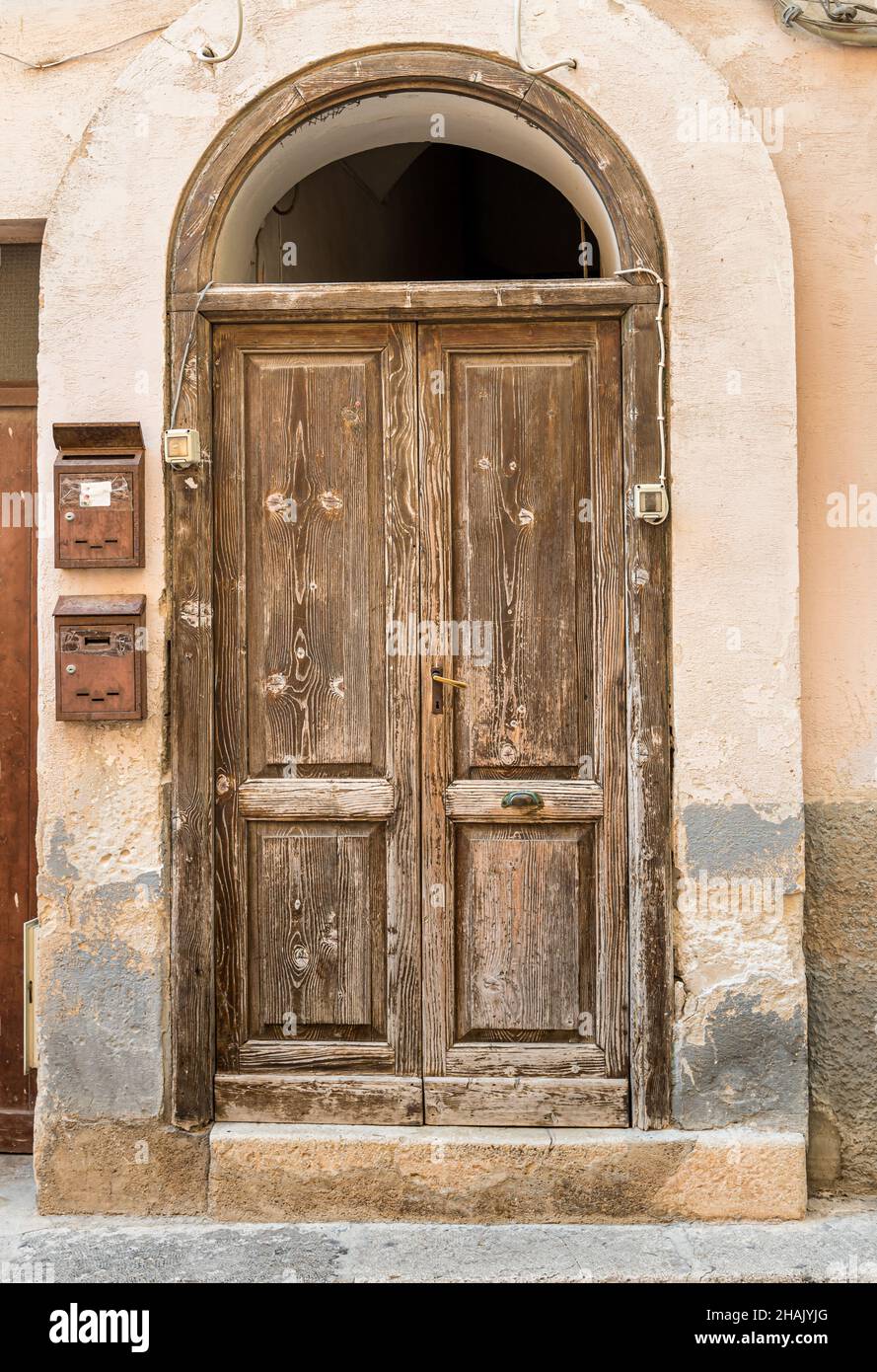 Antica porta in legno della tipica antica casa in pietra mediterranea in Sicilia. Foto Stock