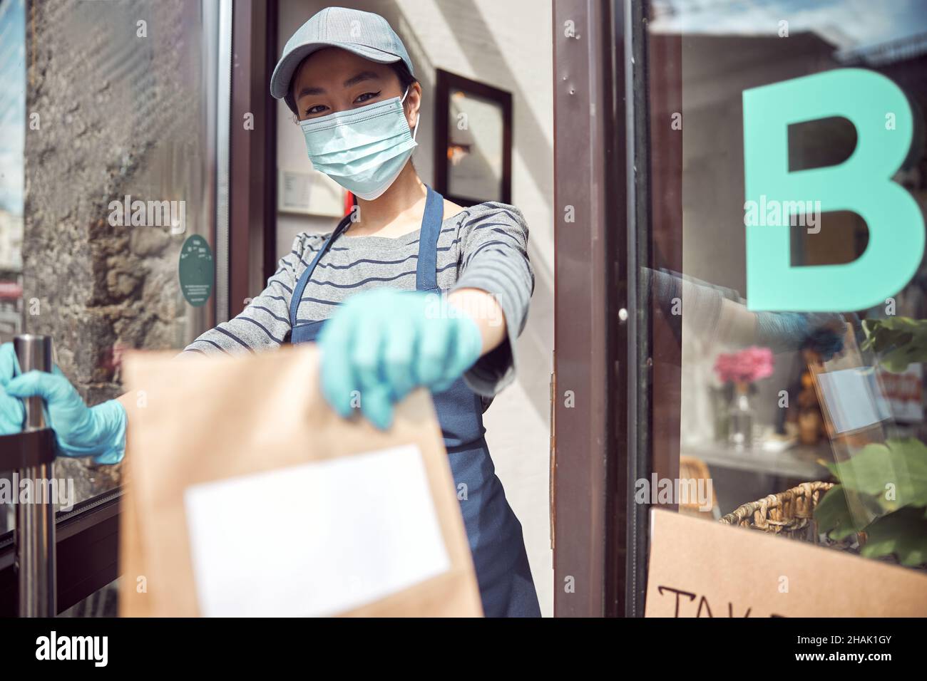 Cameriera asiatica che dà il pasto da asporto al cliente all'aperto Foto Stock