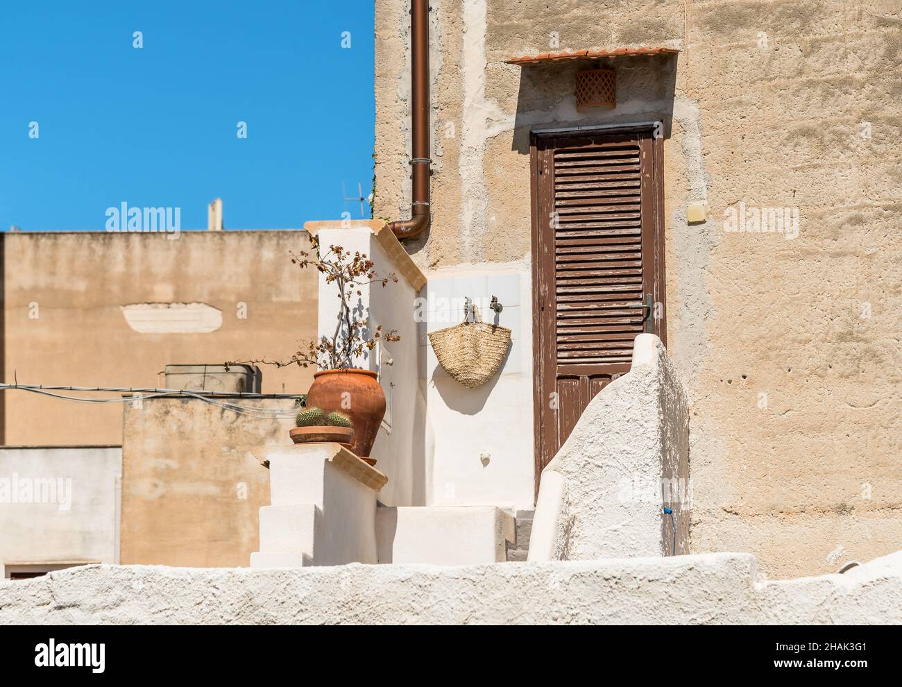 Ingresso con antica porta in legno della tipica antica casa in pietra mediterranea in Sicilia Foto Stock