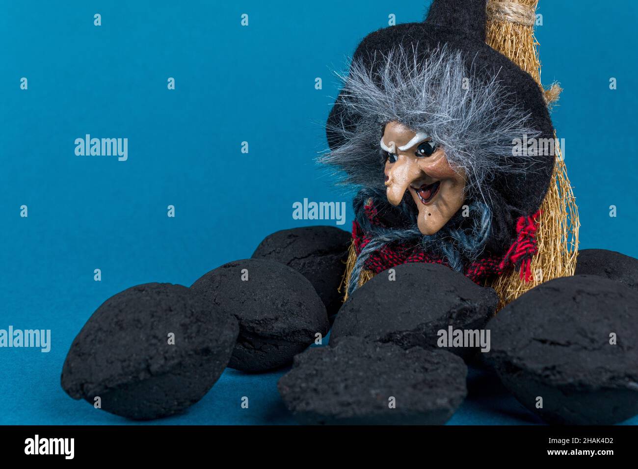 Epifania concetto di vacanza. Strega Befana e pezzi di carbone per bambini naughty su sfondo blu. Spazio di copia. Foto Stock