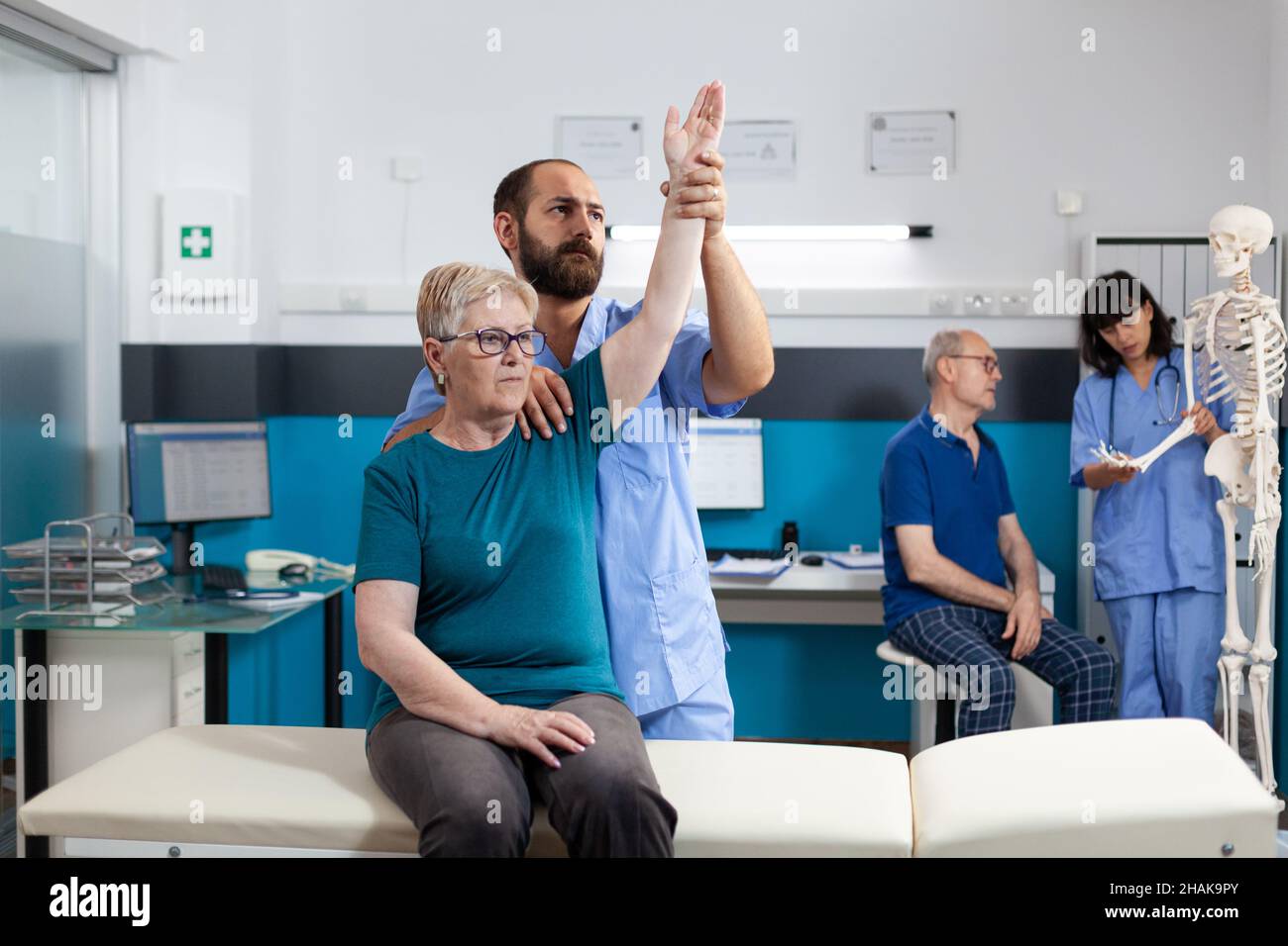 Infermiera ortopedica braccio di paziente anziano con lesioni in ufficio medico. Chiropractor aiutare la donna con dolore del muscolo della spalla per il recupero fisico. Persona alla fisioterapia Foto Stock