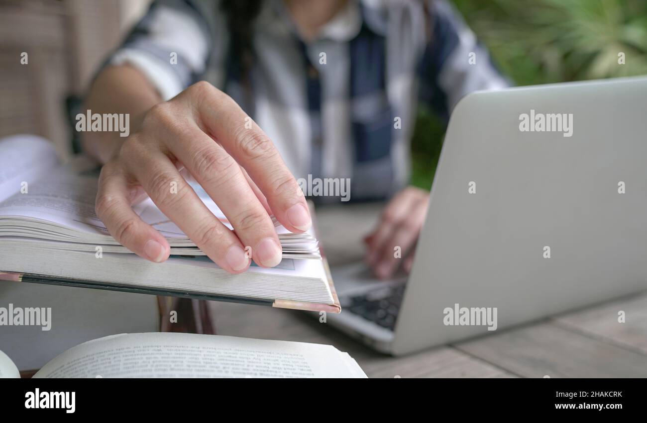 Mano della donna che gira pagine di un libro, primo piano. Impostazione Home. Foto Stock