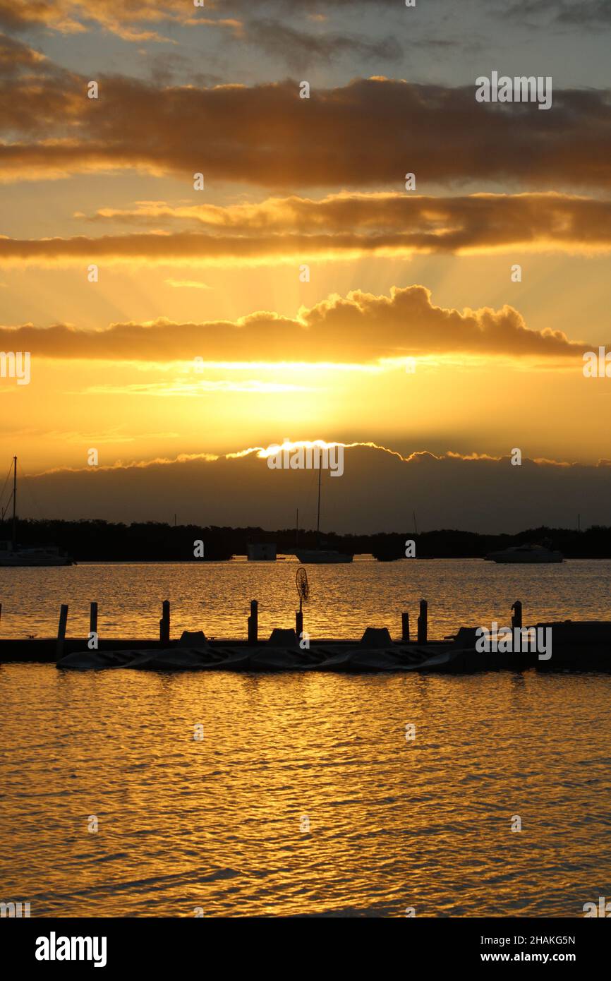 Fasci di luce brillano attraverso le nuvole durante l'alba e si riflettono fuori dall'acqua in Key West Florida. Foto Stock