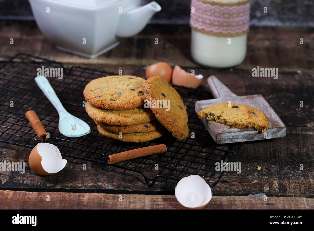 Imburrare i biscotti su una griglia da forno con una teiera e il latte  sullo sfondo Foto stock - Alamy