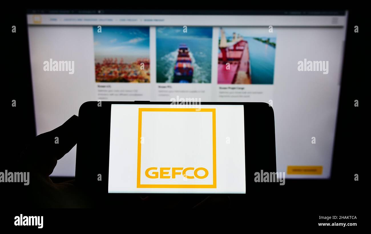 Persona che tiene il cellulare con il logo della società logistica francese GEFCO Group sullo schermo di fronte al sito web aziendale. Mettere a fuoco sul display del telefono. Foto Stock
