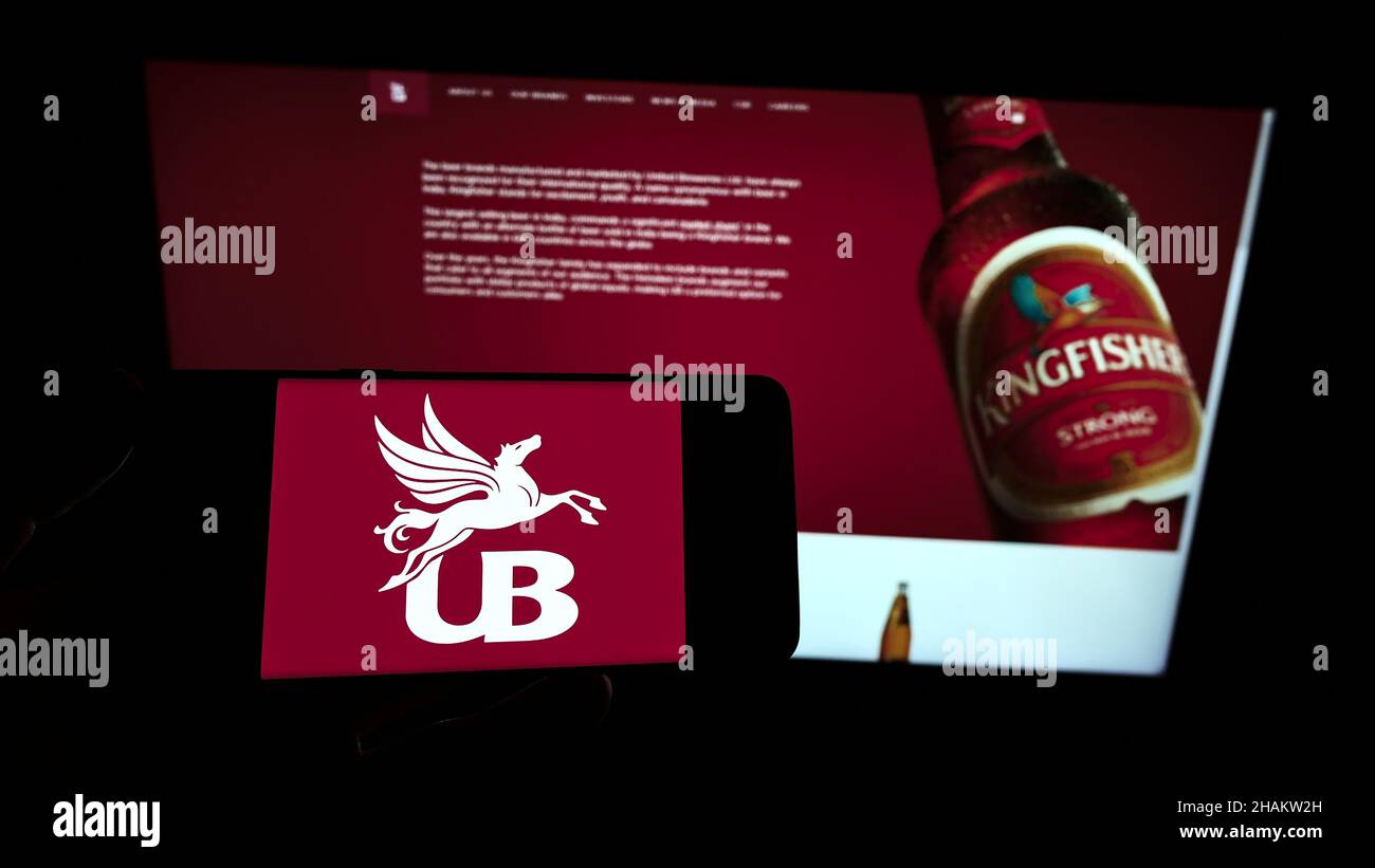 Persona che tiene uno smartphone con il logo della società United Breweries Holdings Limited (UBHL) sullo schermo di fronte al sito Web. Mettere a fuoco sul display del telefono. Foto Stock