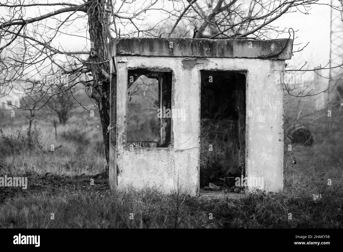 Immagine della profondità di campo poco profonda (fuoco selettivo) con un edificio abbandonato in un campo vicino a una vecchia ferrovia in una giornata invernale. Foto Stock