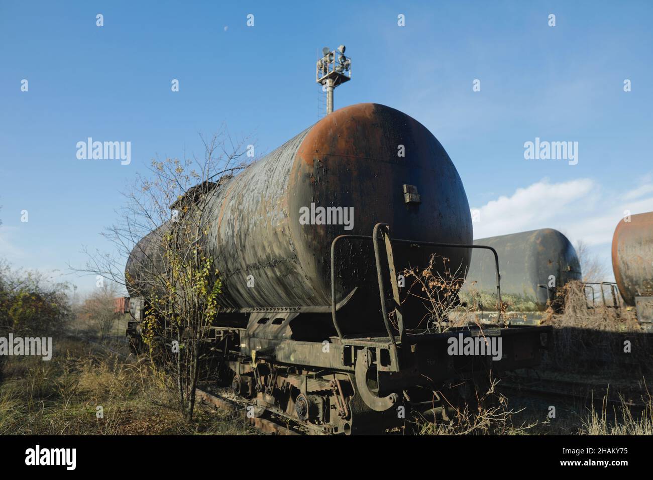 Profondità di campo bassa (fuoco selettivo) immagine con vecchia e arrugginita petroliera ferroviaria nel mezzo di un campo in una giornata invernale soleggiata. Foto Stock