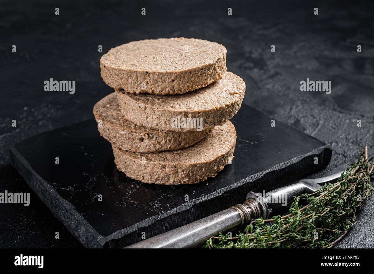 Cotolette di hamburger non cotte a base di carne vegetale, polpette vegane crude. Sfondo nero. Vista dall'alto Foto Stock