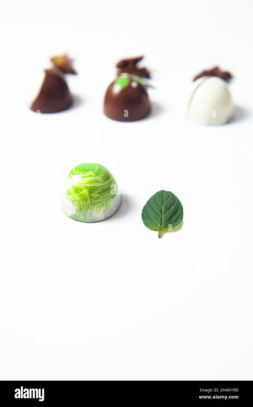 Bonbon di caramelle al cioccolato messicano colorato con foglie di menta, cannella e chicchi di caffè su sfondo bianco Foto Stock