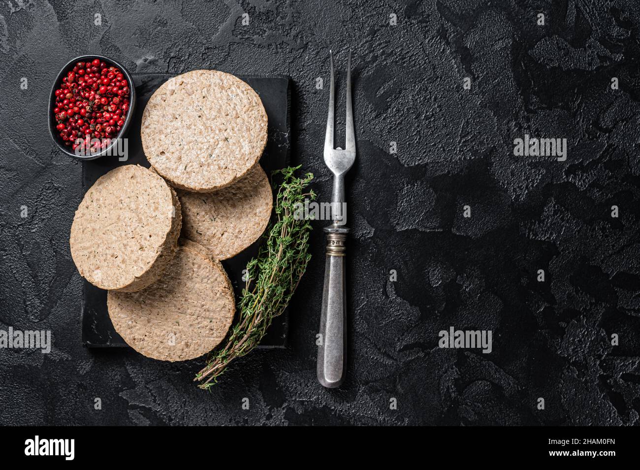 Cotolette di hamburger non cotte a base di carne vegetale, polpette vegane crude. Sfondo nero. Vista dall'alto. Spazio di copia Foto Stock