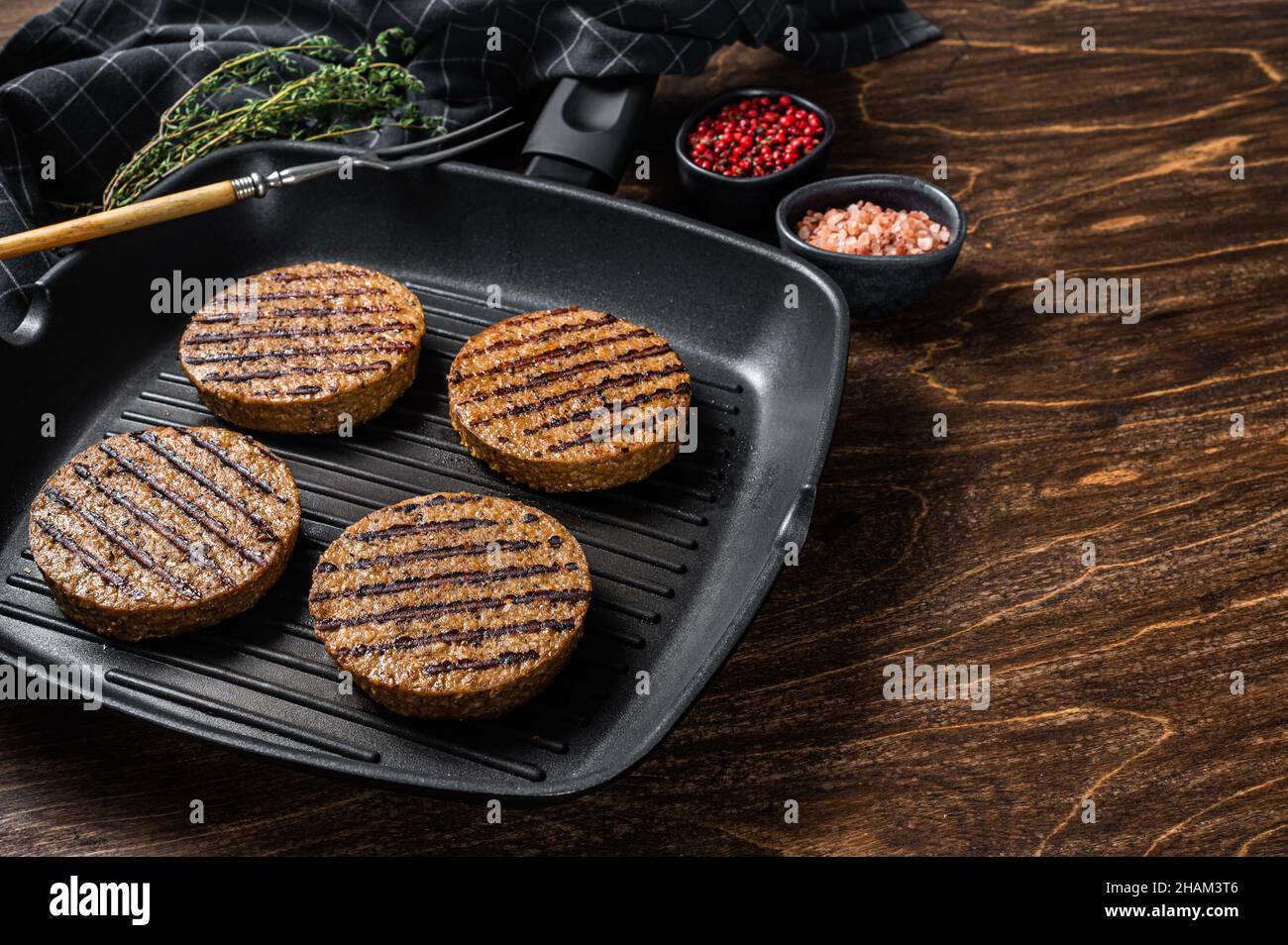 Tortini di hamburger di carne a base di piante vegetariane alla griglia, cotolette di vegano sulla padella alla griglia. Sfondo in legno. Vista dall'alto. Spazio di copia Foto Stock