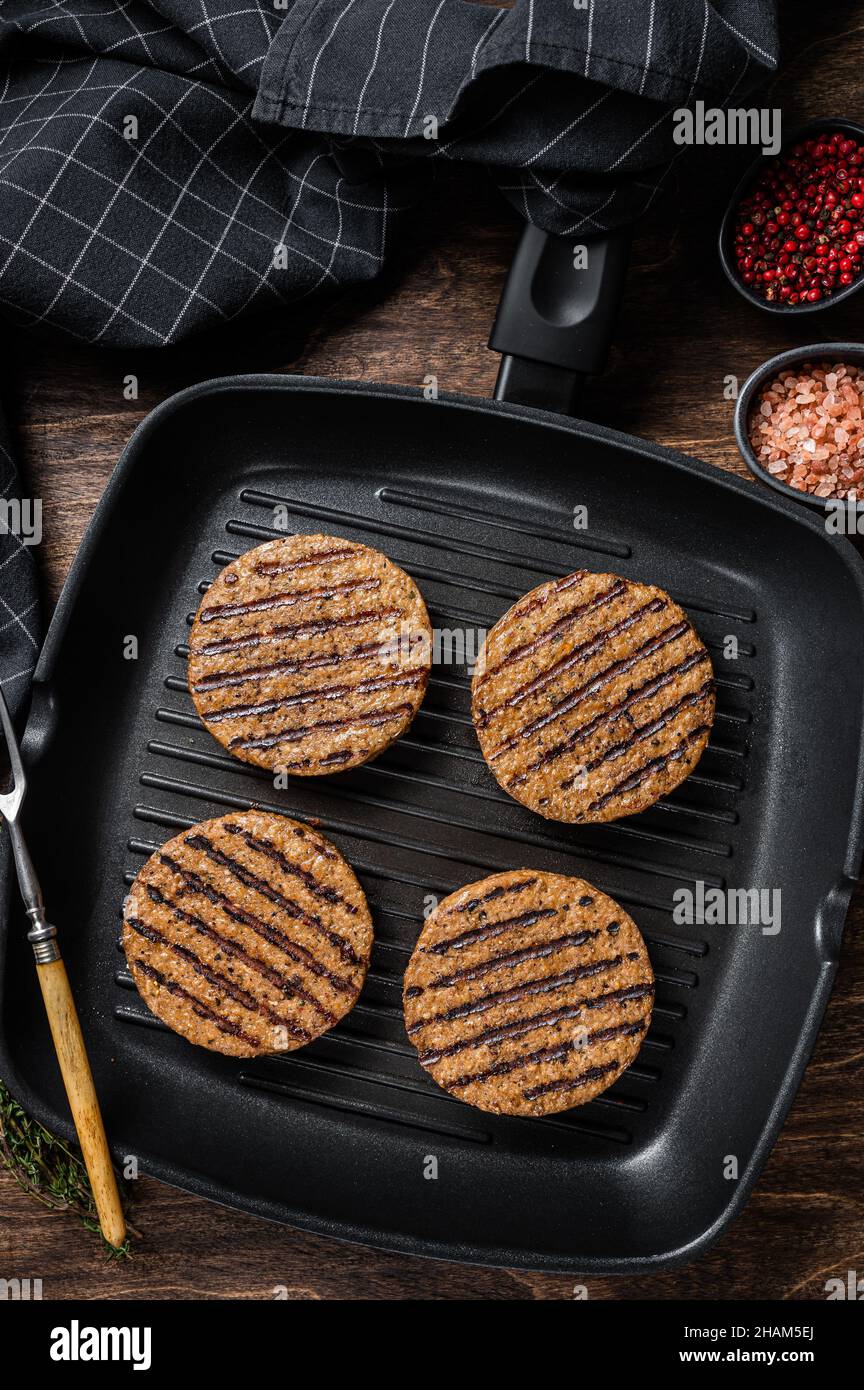 Tortini di hamburger di carne a base di piante vegetariane alla griglia, cotolette di vegano sulla padella alla griglia. Sfondo in legno. Vista dall'alto Foto Stock