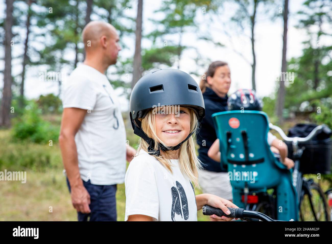 Ragazza sorridente che indossa il casco da ciclismo guardando la macchina fotografica Foto Stock