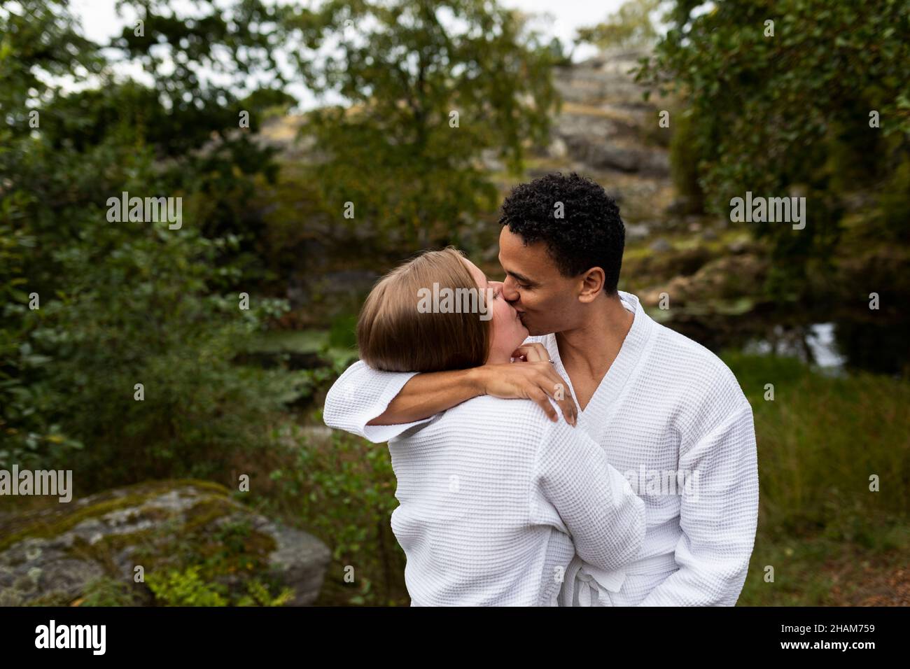 Giovane coppia in accappatoi abbracciare e baciare Foto Stock
