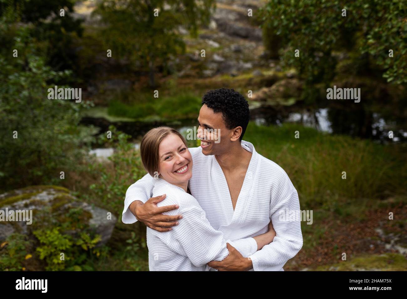 Giovane coppia in accappatoi abbracciante e sorridente Foto Stock