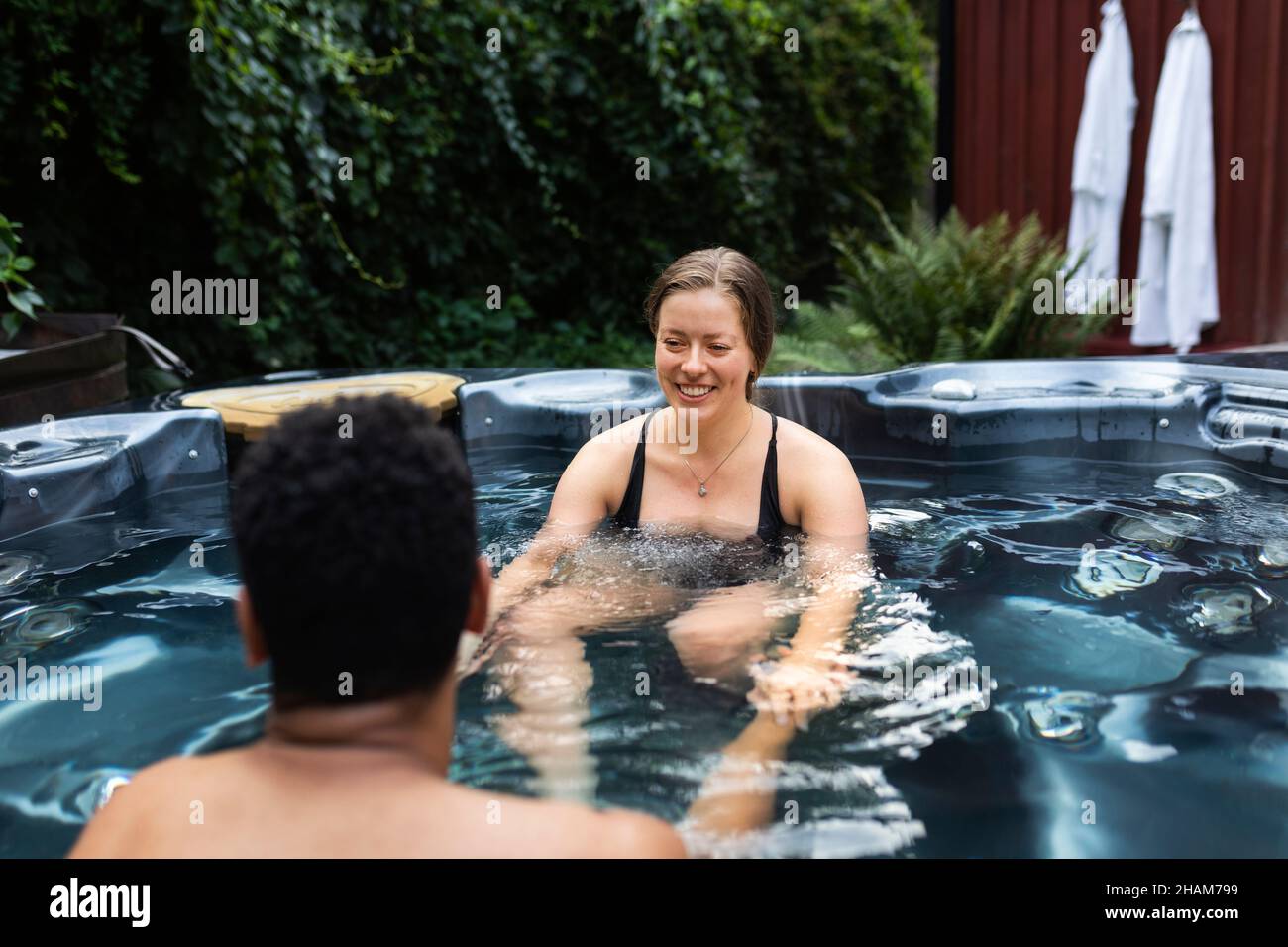 Coppia sorridente seduta nella jacuzzi Foto Stock