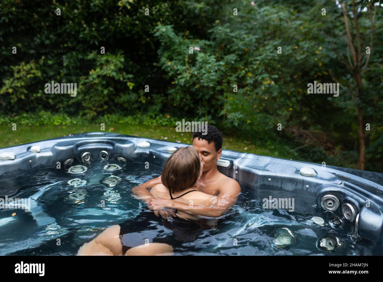 Una giovane coppia bacia nella jacuzzi Foto Stock