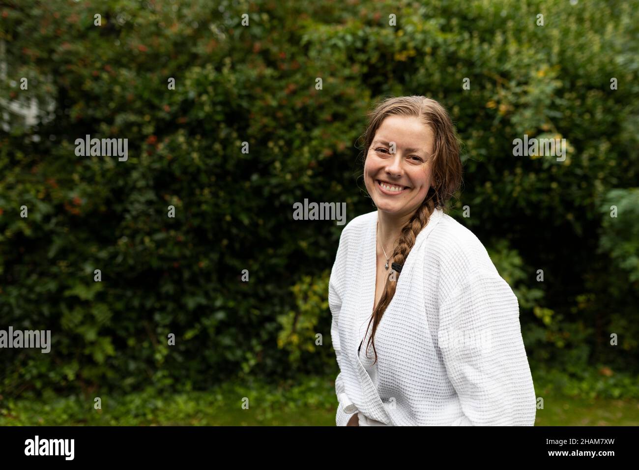 Ritratto di sorridente giovane donna in accappatoio bianco Foto Stock