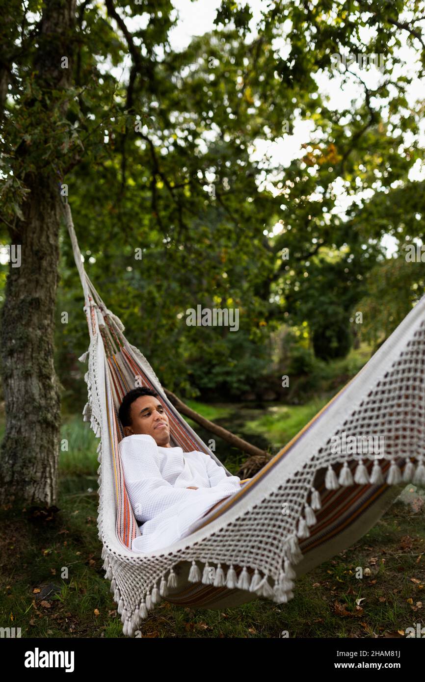 Giovane uomo in accappatoio rilassante in amaca Foto Stock