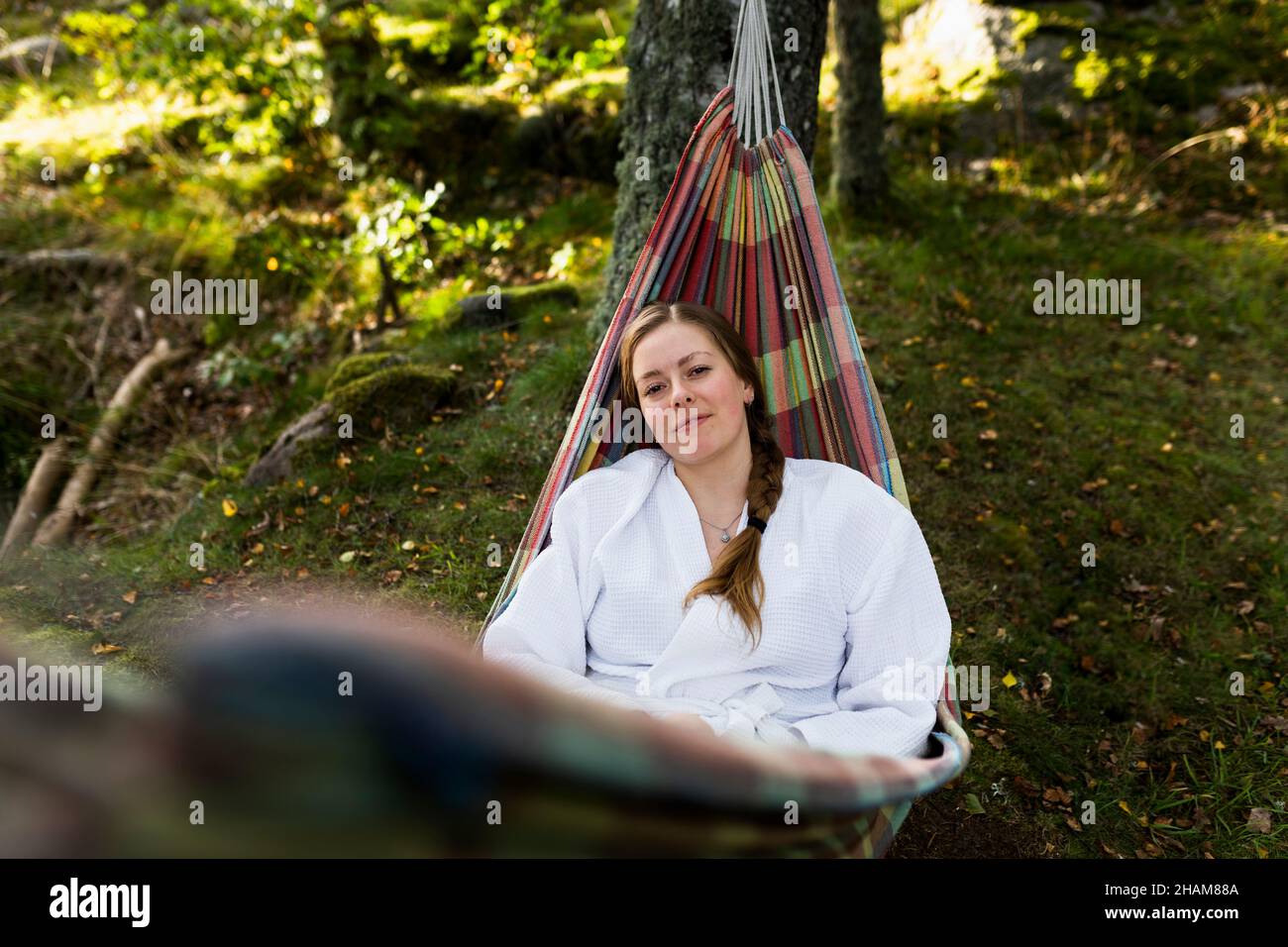 Giovane donna in accappatoio rilassante in amaca Foto Stock