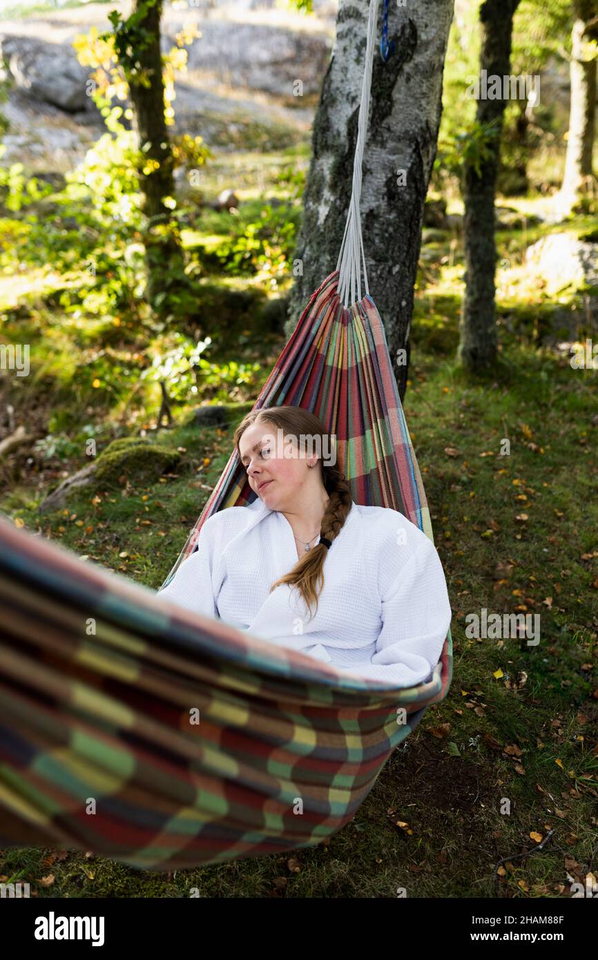 Giovane donna in accappatoio rilassante in amaca Foto Stock