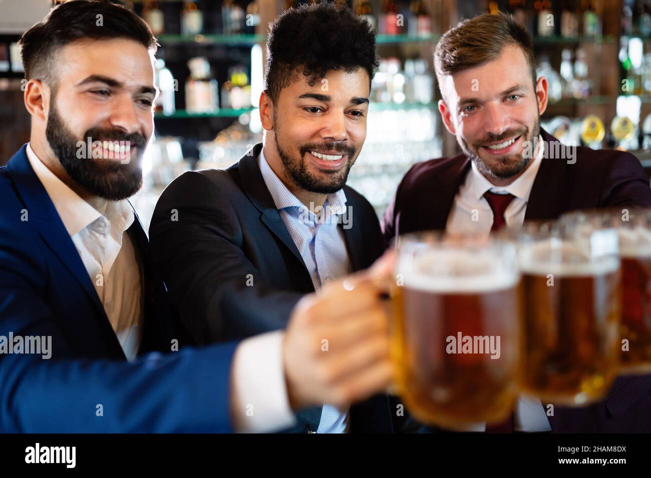 Vecchi amici allegri che si divertono e bevono birra al banco bar nel pub. Foto Stock