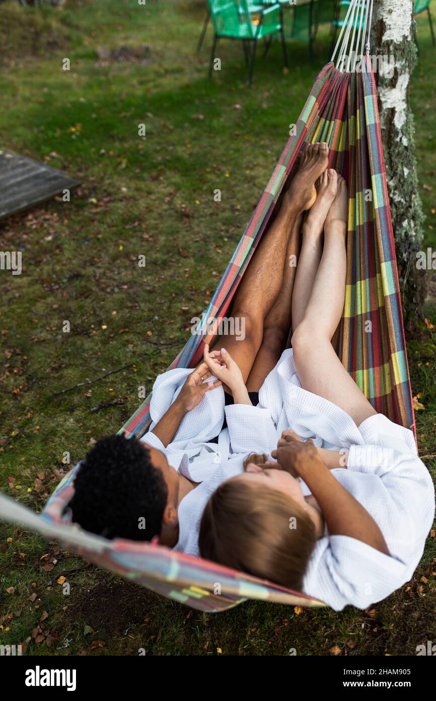 Coppia giovane in accappatoi rilassante in amaca Foto Stock
