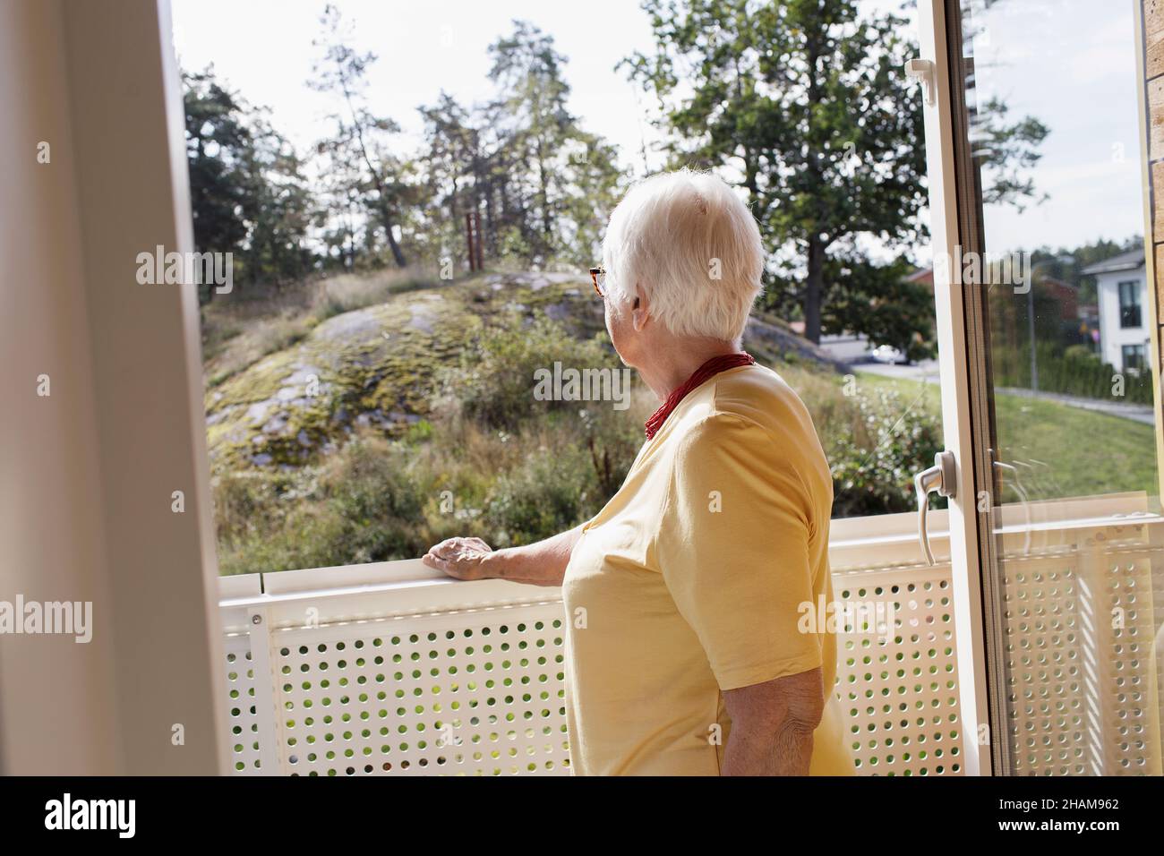 Donna sul balcone che guarda lontano Foto Stock