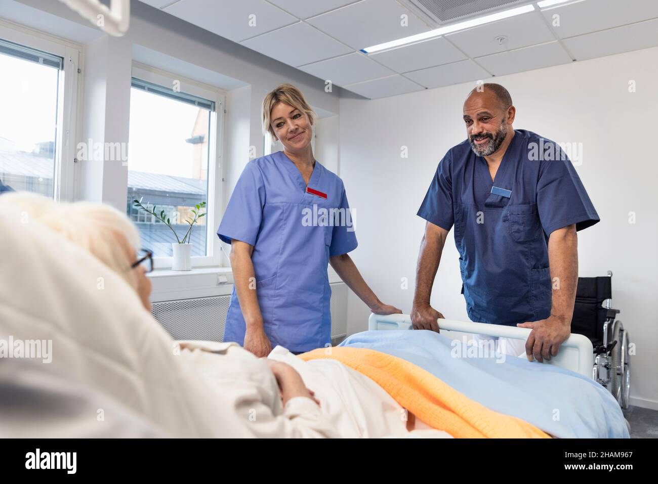 Infermieri che parlano con il paziente sul letto dell'ospedale Foto Stock