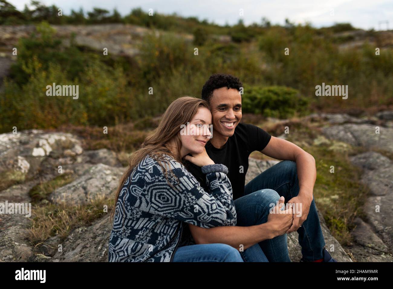 Coppia sorridente seduta sulle rocce Foto Stock
