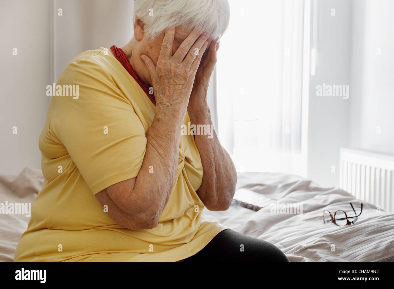 Donna anziana con mani che coprono il viso Foto Stock