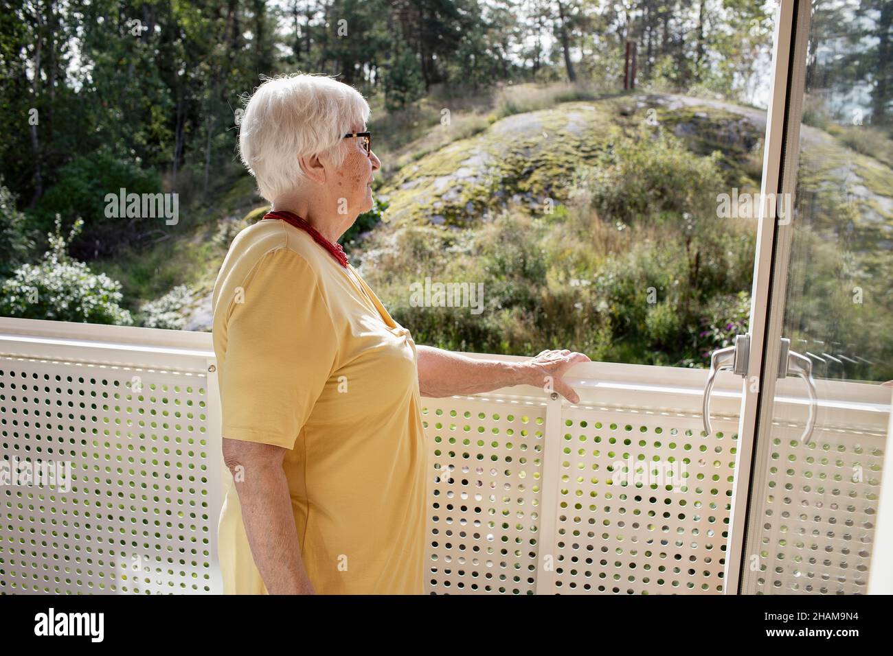 Donna sul balcone che guarda lontano Foto Stock