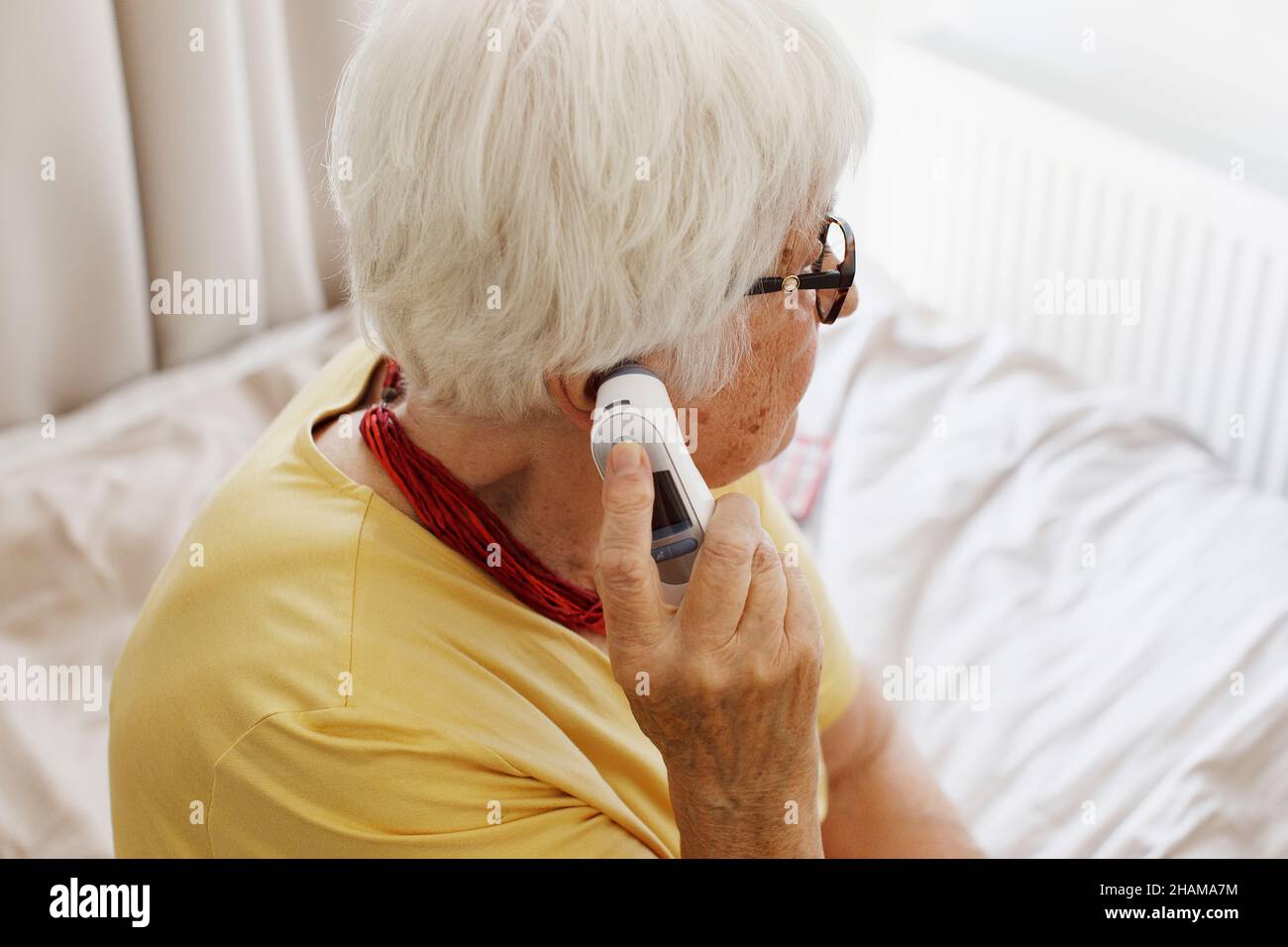 Donna anziana che controlla la temperatura Foto Stock