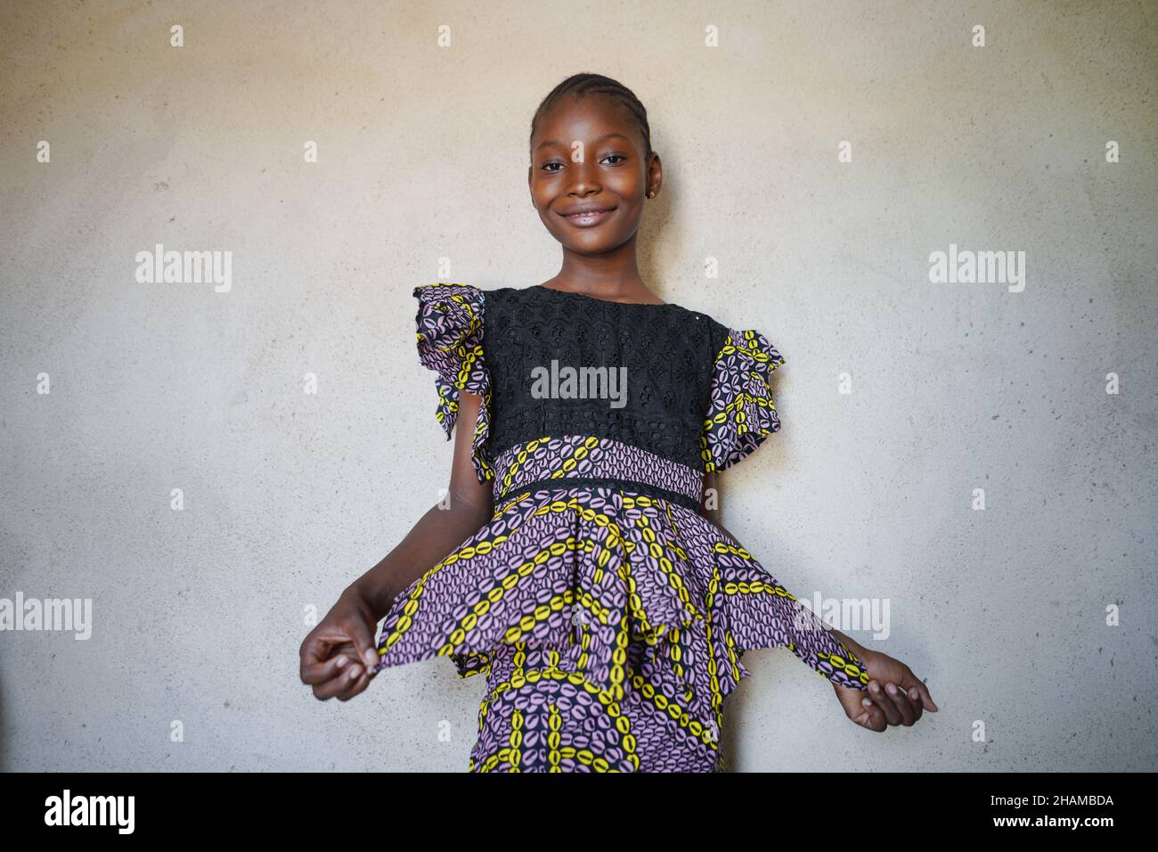 Ritratto giovane ragazza africana bello sorriso e posa con abito tradizionale colorato da sfondo bianco parete Foto Stock