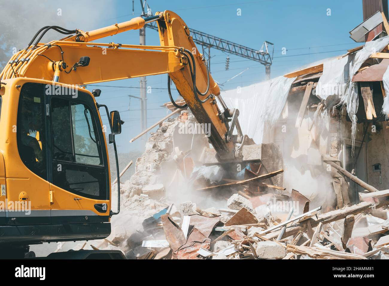 La benna dell'escavatore rompe la vecchia casa. Demolizione di edifici per ristrutturazione. Foto Stock