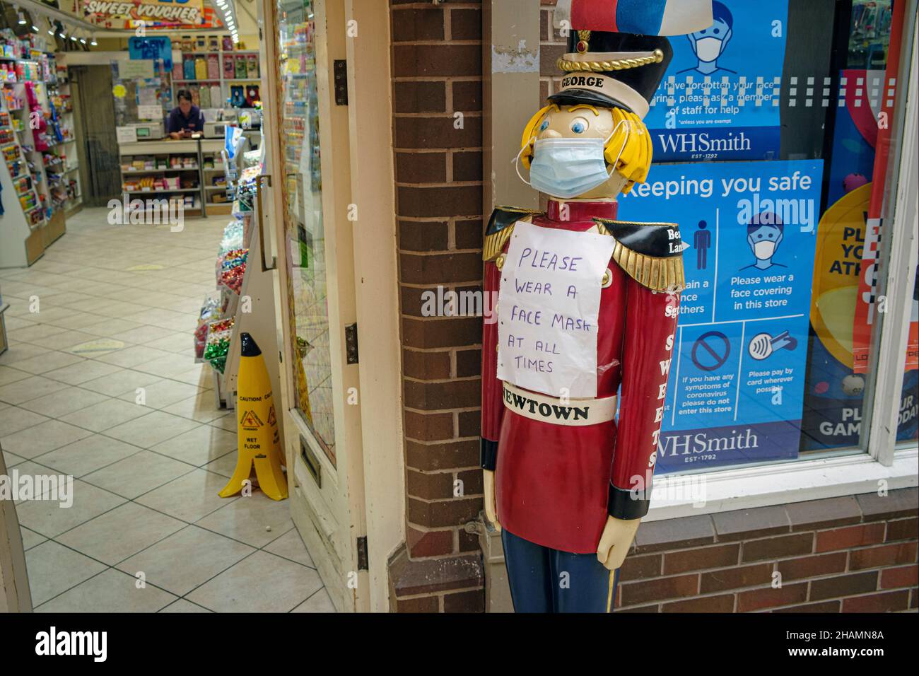 'Si prega di indossare sempre una maschera facciale' - un cartello all'esterno di un negozio di dolci durante la pandemia di Covid-19 a Newtown, Powys, Galles, 2021 Foto Stock