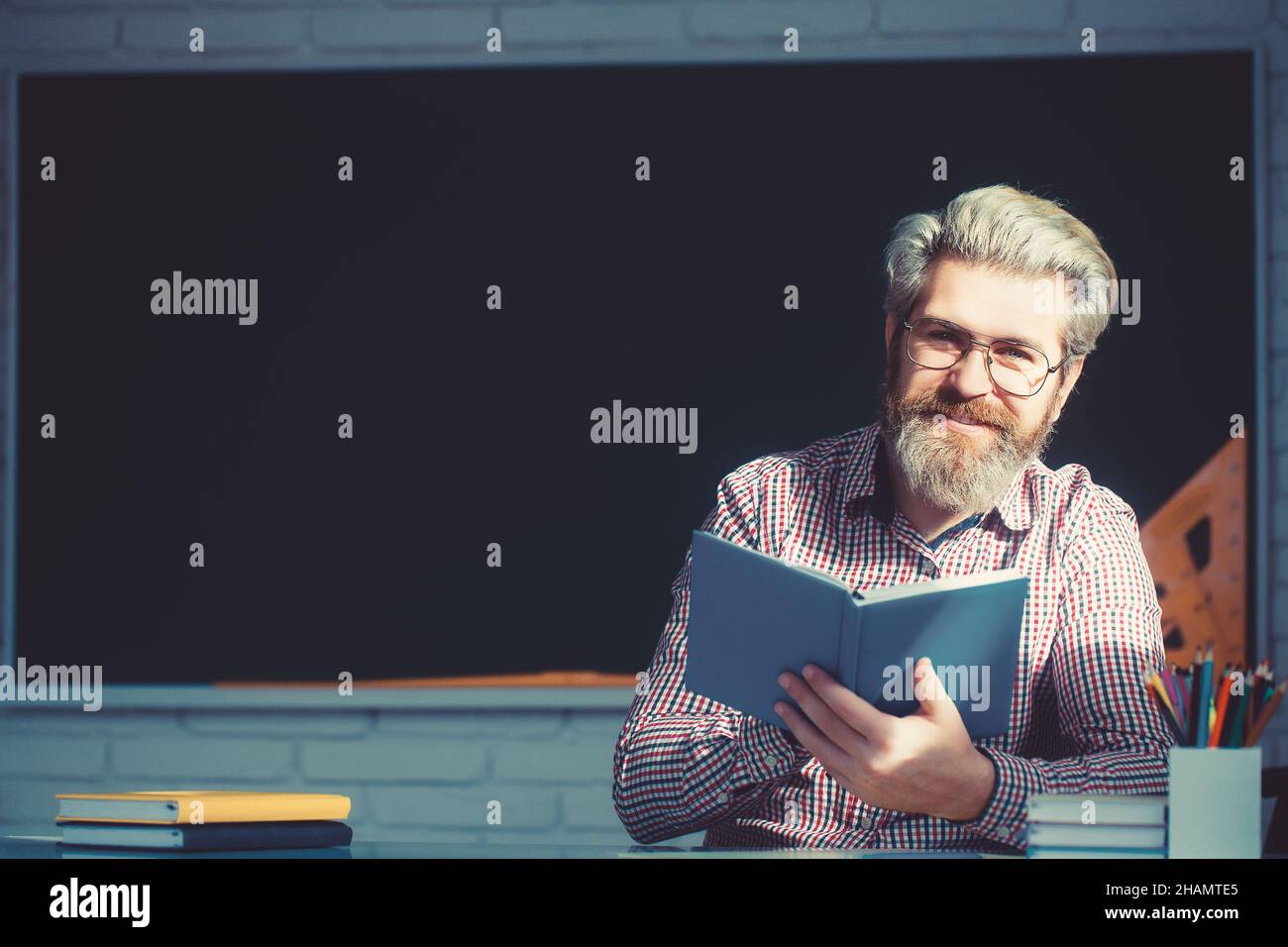 Uomo anziano sorridente che legge libro e sorriso. Foto Stock