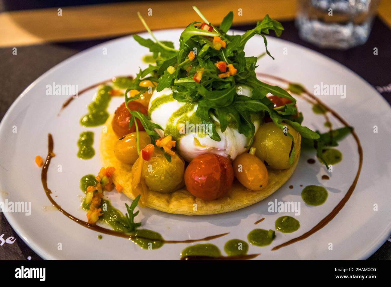 Una torta con burrata, pomodorini rossi arrostiti e rucola viene servita in un bistrot a Tourtour, dipartimento di Var, Francia. Foto Stock
