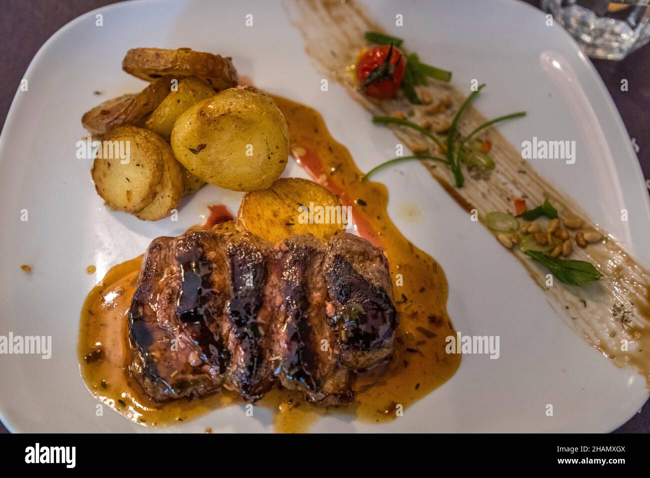 Un piatto di carne grigliata con patate al rosmarino e una salsa viene servito in un bistrò a Tourtour, dipartimento di Var, Francia. Foto Stock