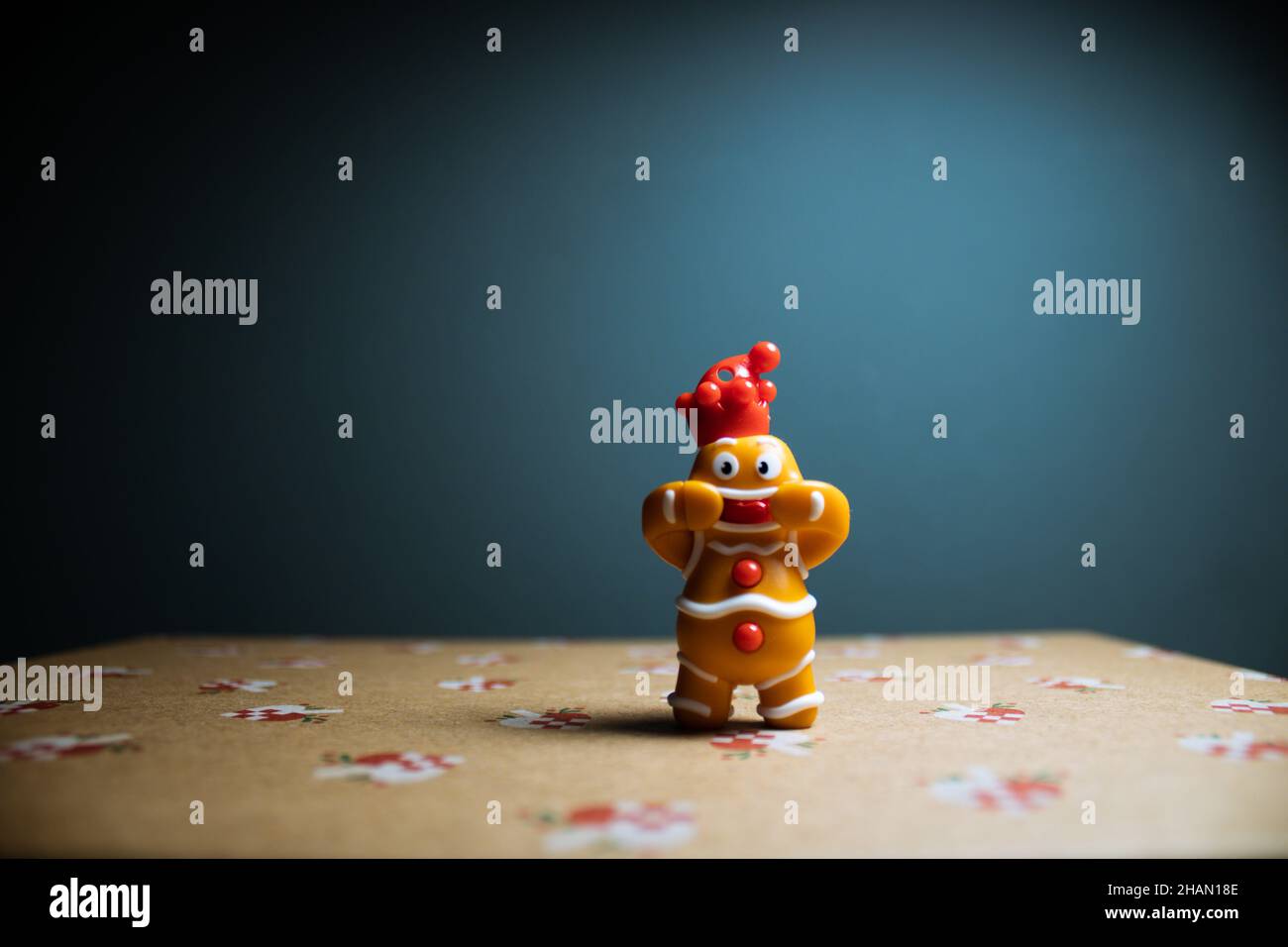 Uomo di pan di zenzero sorridente su un regalo di Natale con sfondo blu. Decorazione per l'anno nuovo, giocattoli di Natale per i bambini Foto Stock